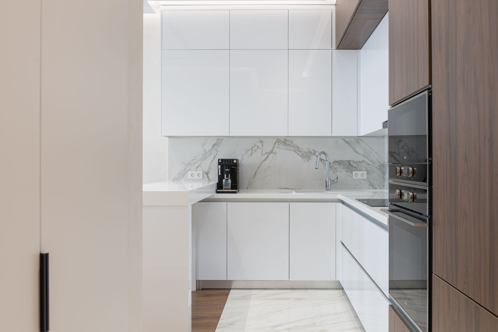 Minimalist interior of small kitchen with white and wooden cupboards and modern appliances in light apartment