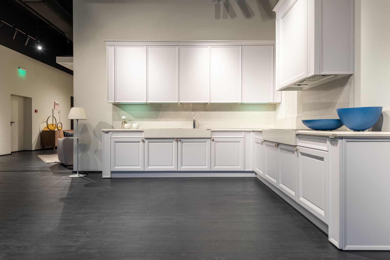 Contemporary stylish kitchen units of white color represented in modern spacious furniture showroom